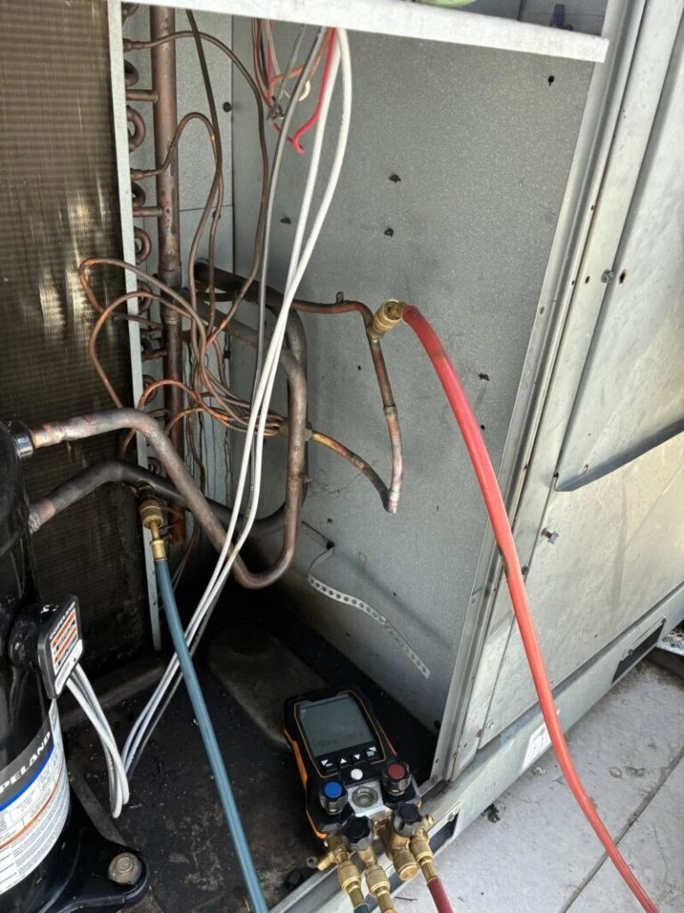 Manifold gauges connected to a rooftop commercial chiller during service in Waco, TX